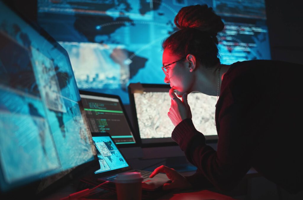woman in cybersecurity role in front of screens